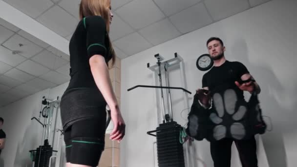 Un uomo veste una donna in una tuta da fitness EMS — Video Stock