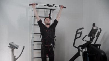 Elektro uyarıcı ekipman takan ve alt karın kaslarını yıkayan bir adam.