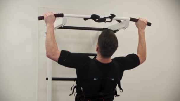 一个穿着带电刺激装置的背心做引体向上的男人 — 图库视频影像