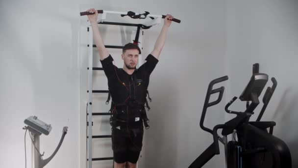 Konzentrierter Mann trägt Elektrostimulationsgeräte und pumpt seine untere Bauchmuskulatur — Stockvideo