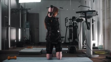 Spor salonunda takım elbiseyle antrenman yapan genç bir kadın.