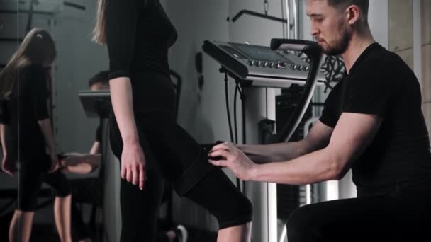 Een man kleedt een vrouw in een elektrisch stimulatie fitness pak — Stockvideo