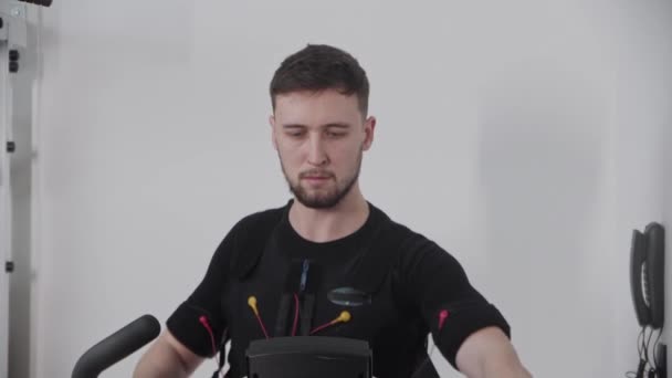 Een man in een elektrisch stimulatiepak aan het trainen in de lokale sportschool. — Stockvideo