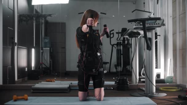 Mujer joven entrenando sus manos en traje de ems en el gimnasio — Vídeo de stock
