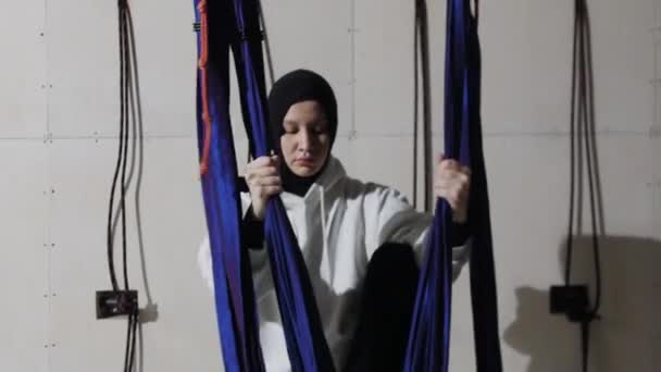 Une jeune femme dans le hijab utilise l'hamac de yoga dans le studio — Video