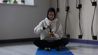 Tesettürlü genç bir kadın, yoga minderinin kenarlarında torbacıyı götürerek meditasyon ritüeli yapıyor.