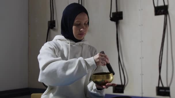 Une jeune femme en hijab fait un rituel avec la conduite du pousseur le long des bords du réservoir — Video