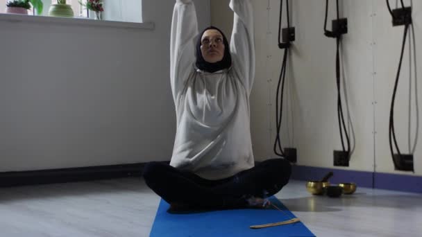 A woman in hijab meditating with smoldering incense on yoga mat — Stock Video