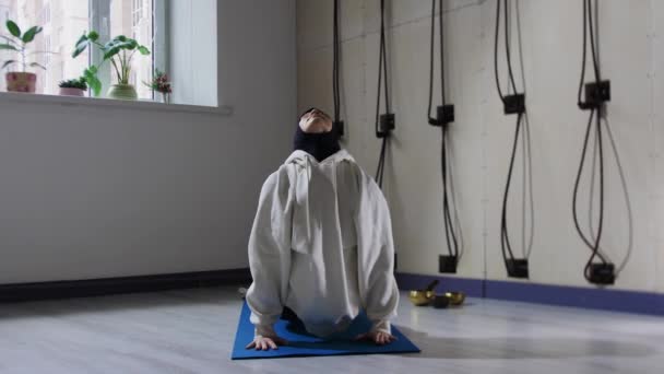 A woman in hijab doing yoga for her back and spine on yoga mat — Stock Video