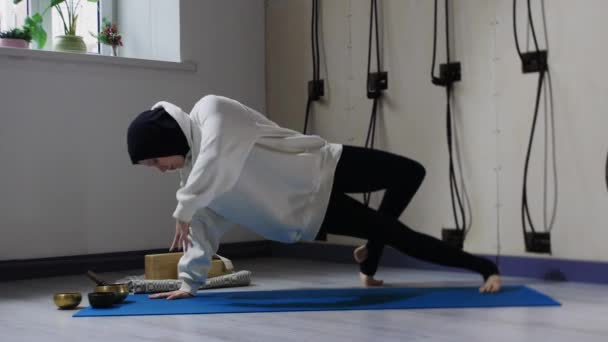 En ung kvinna i hijab tränar yoga på yogamatta — Stockvideo