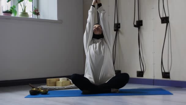 Молодая женщина в хиджабе медитирует и поворачивает голову в сторону — стоковое видео