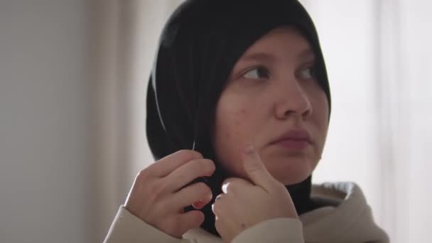 A fiatal nő megjavítja a hidzsábját, aztán belenéz a kamerába. — Stock videók