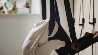 Yoga hamağında sallanan ve egzersiz yapan tesettürlü genç bir kadın.