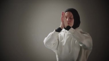 Yoga - genç bir müslüman kadın meditasyon yapıyor sonra kameraya bakıyor.