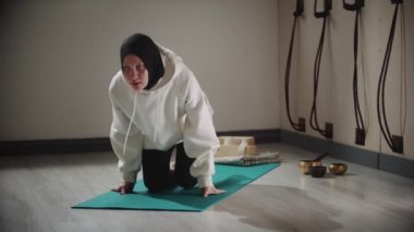 Yoga içeride - tesettürlü genç bir kadın tahtada duruyor