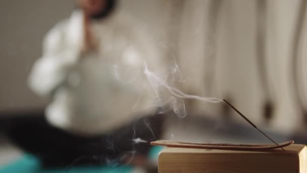 Smoldering incense and a woman meditating on the floor — Stock Video