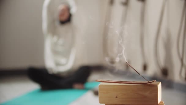 Jóga - mladá žena v hidžábu meditující s doutnajícím kadidlem na popředí — Stock video
