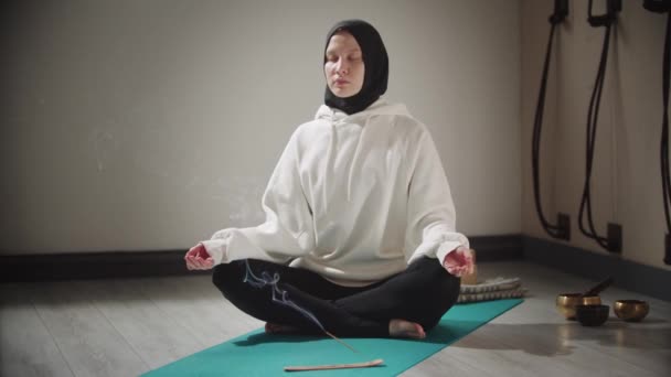 Yoga - a young muslim woman meditating with smoldering incense on the floor — Stock Video