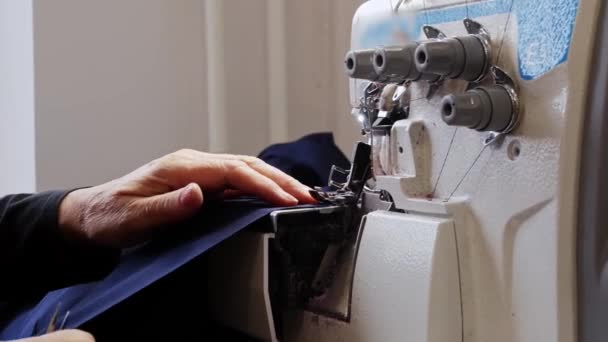 Старуха шьет синюю одежду на швейной машинке. — стоковое видео