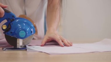 Genç bir kadın otomatik daire kesicisiyle kumaş kesiyor. Orta çekim