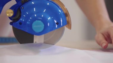 Otomatik daire kesiciyle kumaşı kesiyor. Orta çekim