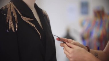 Bir kadın tasarımcı siyah bir cekete pul yapıştırır.