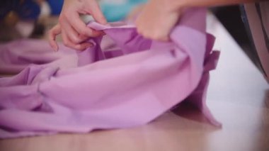 Kadınların elleri pembe kumaşa iğne batırır.