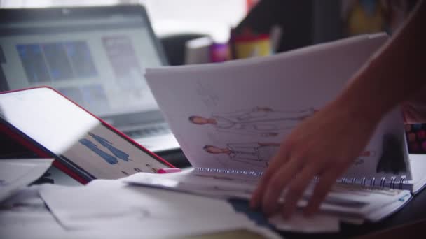 28-02-2022 RUSSIA, KAZAN：一位女设计师翻阅着素描和服装图纸的草图 — 图库视频影像