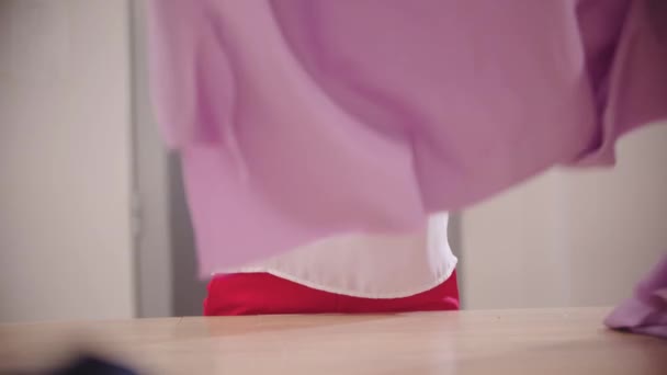 Uma mulher designer trabalha com tecido rosa púrpura à mesa — Vídeo de Stock