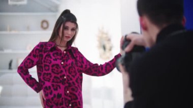 Pembe leopar takım elbiseli güzel bir kadın beyaz stüdyoda fotoğraf çekiyor. Orta çekim