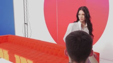 01-03-22 RUSSIA, KAZAN: kamera için kırmızı bir koltukta şekillendirme ve makyaj yapan genç ve güzel bir model. Orta çekim