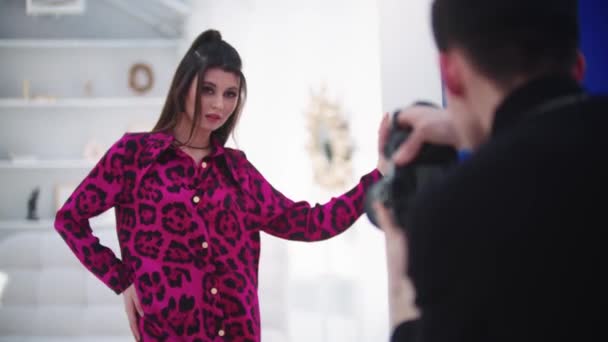 穿着粉色豹衣的年轻漂亮女模特在白工作室拍照 — 图库视频影像