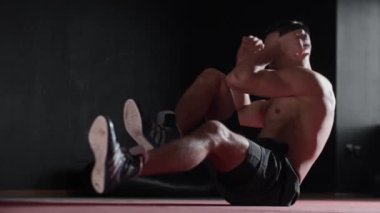 Spor salonunun zemininde çalışan zinde bir genç. Orta çekim
