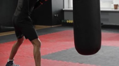 Sporcu genç boksör spor salonunda kum torbasına vuruyor. Orta çekim