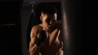 Boks eğitimi - formda olmayan, boks eldiveni giyen, kum torbasını yumruklayan bir adam. Orta çekim