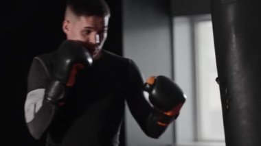 Genç formda adam kum torbasına vuruyor. Orta çekim