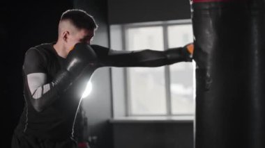 Spor salonundaki zinde adam kum torbasına vuruyor. Orta çekim