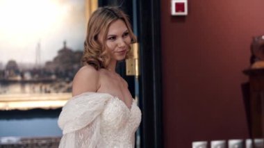 Sarışın, stil sahibi, düğünlü ve müzede poz veren bir kadın. Orta çekim