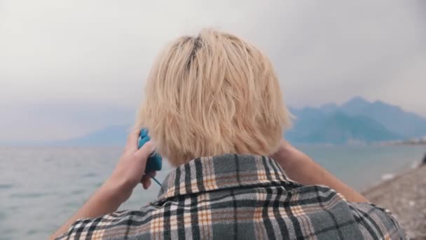 Blondyn Koszuli Kratę Siedzi Brzegu Zakłada Słuchawki Głowę Środek Strzału — Wideo stockowe