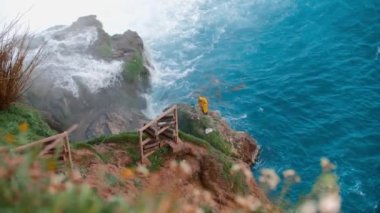 Sarı yağmurluklu bir işçi şelalede taşları temizler. Orta çekim