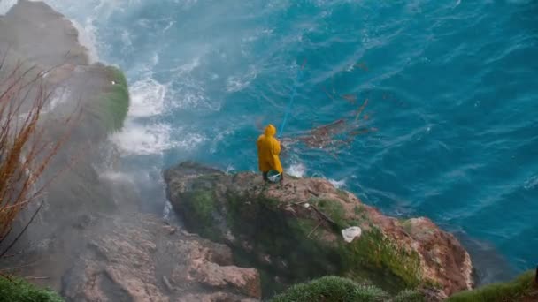 Seorang Pria Dalam Mantel Hujan Kuning Memancing Berdiri Atas Batu — Stok Video