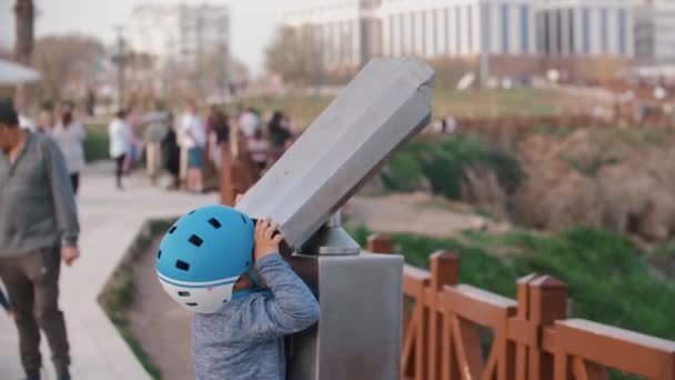 Een Jongetje Kijkt Door Een Telescoop Naar Een Waterval Tussenschot — Stockvideo
