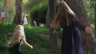 Anne ve iki kızından oluşan mutlu bir aile parkta kovalamaca oynuyor ve sonunda sarılıyorlar. Orta çekim
