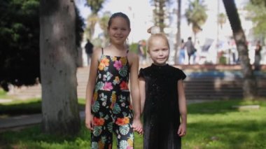 Parkta durmuş kameraya bakan iki küçük kız kardeş. Orta çekim