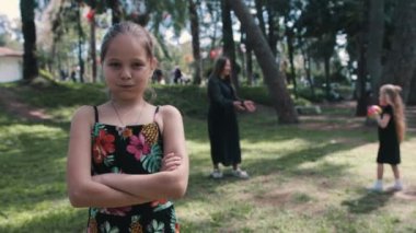 Ailesi top oynarken küçük bir kız kenara çekiliyor ve alınıyor. Orta çekim