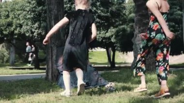 İki küçük kız yeşil parkta telefonunda annelerinin yanına koşuyorlar. Orta çekim