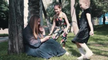 Parkta telefonunda annelerinin yanına koşan iki küçük kız. Orta çekim