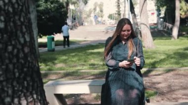 Parkta telefonunu kullanan bir kadın. Orta çekim