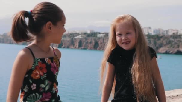 Två Små Flickor Som Sitter Ett Murverk Vid Havet Och — Stockvideo