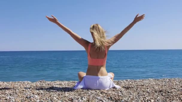 Blonde Woman Meditating Pebble Beach Facing Sea Mid Shot — Stock Video